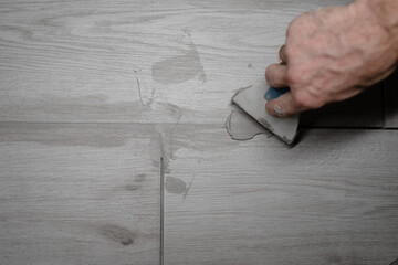 jointing of floor tiles. Grouting tiles seams with a rubber trowel. Grouting ceramic tiles. Tilers...