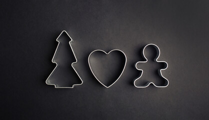 Christmas minimal black background. cookie cutters tree, heart, gingerbread man.