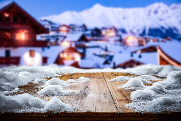 Wooden table in the snow against the backdrop of a mountain landscape at sunset