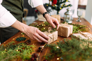 Man hands tying holiday gift box with fir branch
