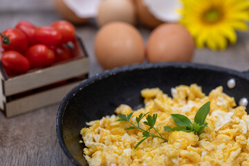 Scrambled eggs in an iron pan on the rustic wooden table