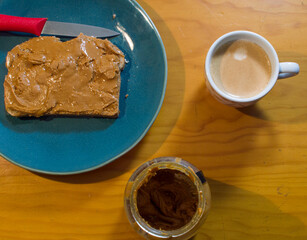 Peanut butter on toast on green plate on wooden table and hot espresso coffee