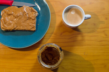 Peanut butter on toast on green plate on wooden table and hot espresso coffee