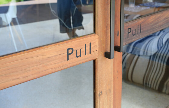 Glass door of restaurant with text pull on wood.