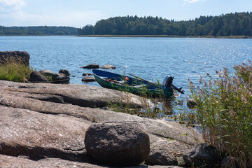 Boat with motor and oars moored to the shore on a forest lake