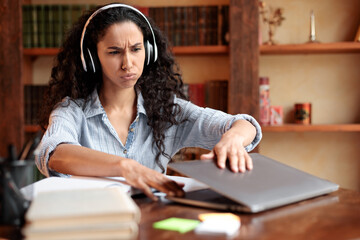 Tired woman sitting at desk, closing or opening laptop