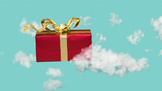 Christmas gift with waving golden ribbon flying in the clouds. Gift on the way to consumer. Online shopping concept. 4K stop motion animation.