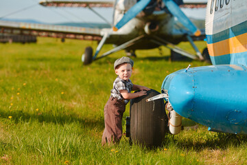 A child stand near an old plane and dreams of becoming a pilot when he grows up. The concept of choosing a future profession