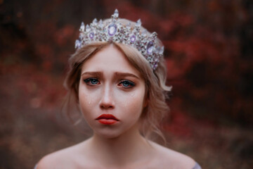 Сlose-up emotional portrait of beautiful sad girl princess crying. Fairy woman medieval queen. Wet red eyes, tears streaming down her cheeks on attractive face. Vintage crown tiara on head blonde hair © kharchenkoirina