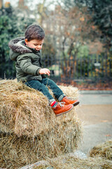 Toddler sitting on the straw bale at a square in London in autumn