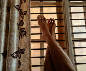 A man seating opposite to window with crossed leg in relaxing mode