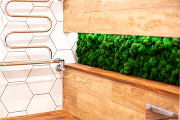 Part of the bathroom with wood grain tiles and artificial green moss. Modern design and decoration of the apartment