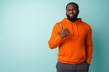 Displeased african american man looking at camera and showing thumb up