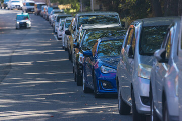 昼の公園の道路で駐車しているたくさんの車