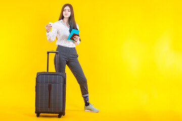 Girl next to a travel suitcase. Concept - a woman checks documents before departure. Girl is considering a ticket. Suitcase as a symbol of long-distance travel. Concept - Woman going on a cruise