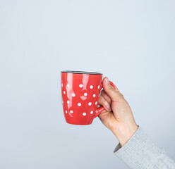 red ceramic cup in a female hand on a white background