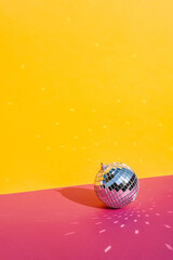 Disco ball of silver color on a bright multi-colored background.