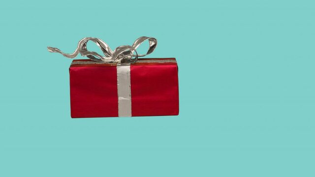 Christmas gift with waving silver ribbon flying on blue background. Gift on the way to consumer. Online shopping concept. 4K stop motion animation.