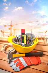 Tools in a yellow helmet on a construction site with a background crane.
