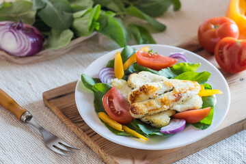 Fresh salad with juicy tomatoes, halloumi cheese, spinach and red onion. Homemade food. Concept for a tasty and healthy meal. Selective focus
