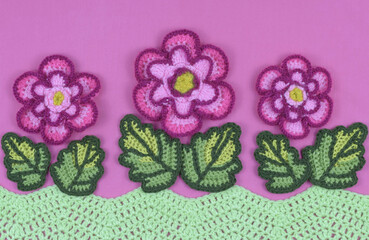 Handmade multicolored flowers and leaves on pink background, creative spring mood card.