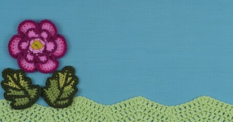 Handmade crochet flower on a blue textile background.