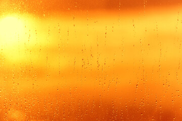 Rain water drops pattern on window glass surface and sunset sky sun