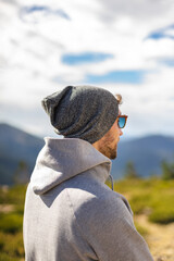 Young white man from behind with sunglasses in a beautiful natural setting surrounded by mountains in a casual style
