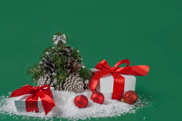 Christmas decorations and gifts on snow on green background with copy space