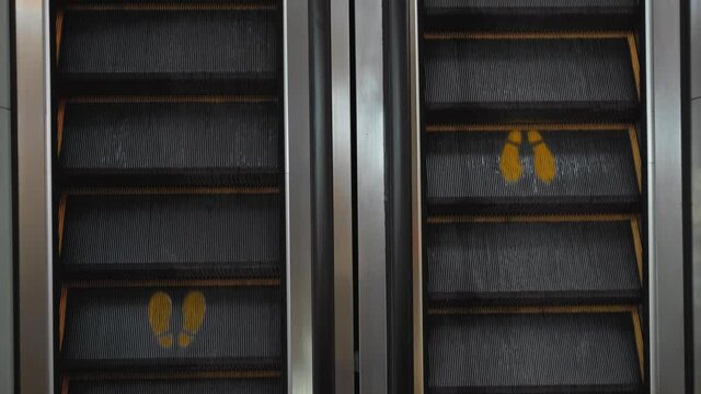 staircase escolator in a shopping center with a footprint sign for keeping a social distance