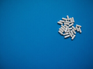 Blue background and white pills in the corner. Copy space. Medical concept