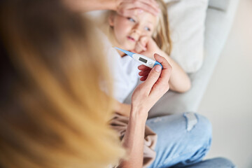 Mother measuring temperature of her ill kid