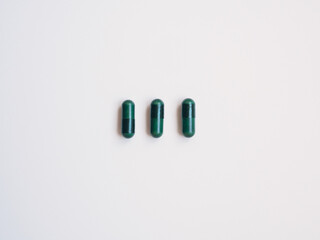 Three green pills, white background. Health concept
