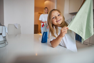 Happy cheerful daughter helping clean apartment her mother at the weekend