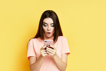 Portrait of a shocked pretty millennial hipster girl using mobile phone