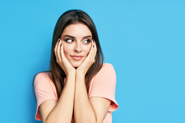 Portrait of shy happy excited female on blue background with copy space