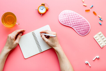 Obraz premium Female hand write in notebook - day plan before sleeping. Top view