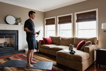Man working out with weights at home using online exercise program.