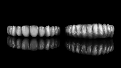 two ready-made dentures for the upper and lower jaw made of ceramic, photo in black and white style on a black background