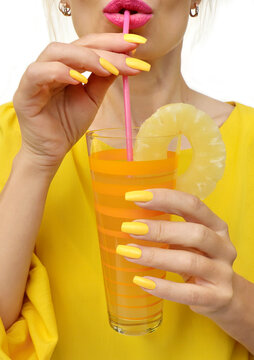 Young Woman Drinking Pineapple Juice With Joy. Trendy Manicure With Yellow Nail Polish On A Long Form.