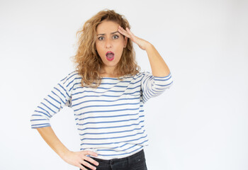 Beautiful woman with facial expression of surprise wearing casual striped t-shirt standing over white background.