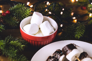 Red Bowl With Tasty Marshmallow Christmas Food or Dessert Christmas Lights and Fir Branches Horizontal Dark Photo