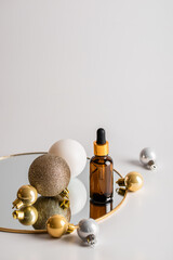 Christmas minimalistic composition with brown glass serum bottle and golden balls on the mirror. Health and beauty concept.
