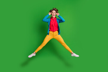 Fototapeta na wymiar Full length body size photo of carefree playful female student jumping high touching eyewear isolated on vivid green color background