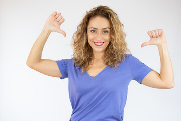 Fototapeta na wymiar Portrait of young smiling woman in casual t-shirt pointing thumbs herself isolated over white background