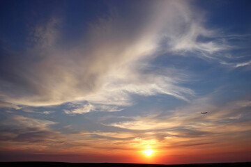 Beautiful sunset with clouds and a flying plane. Travel concept. Copy space for text.