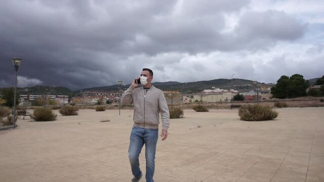 Man wearing reusable face mask using a smartphone in an urban background.