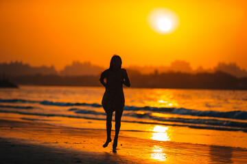 Adorable happy little girl on white beach at sunset.