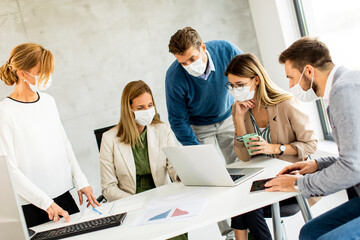 Team of business people working on project with facial masks as a virus protection