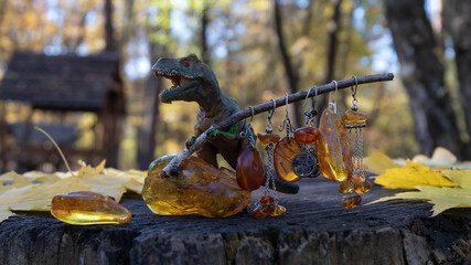 Beautiful yellow old Baltic amber earrings  hang from a twig held in the paws of a dinosaur. Pieces...